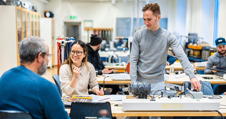 Två studerande i ett klassrum med massor av elprylar.